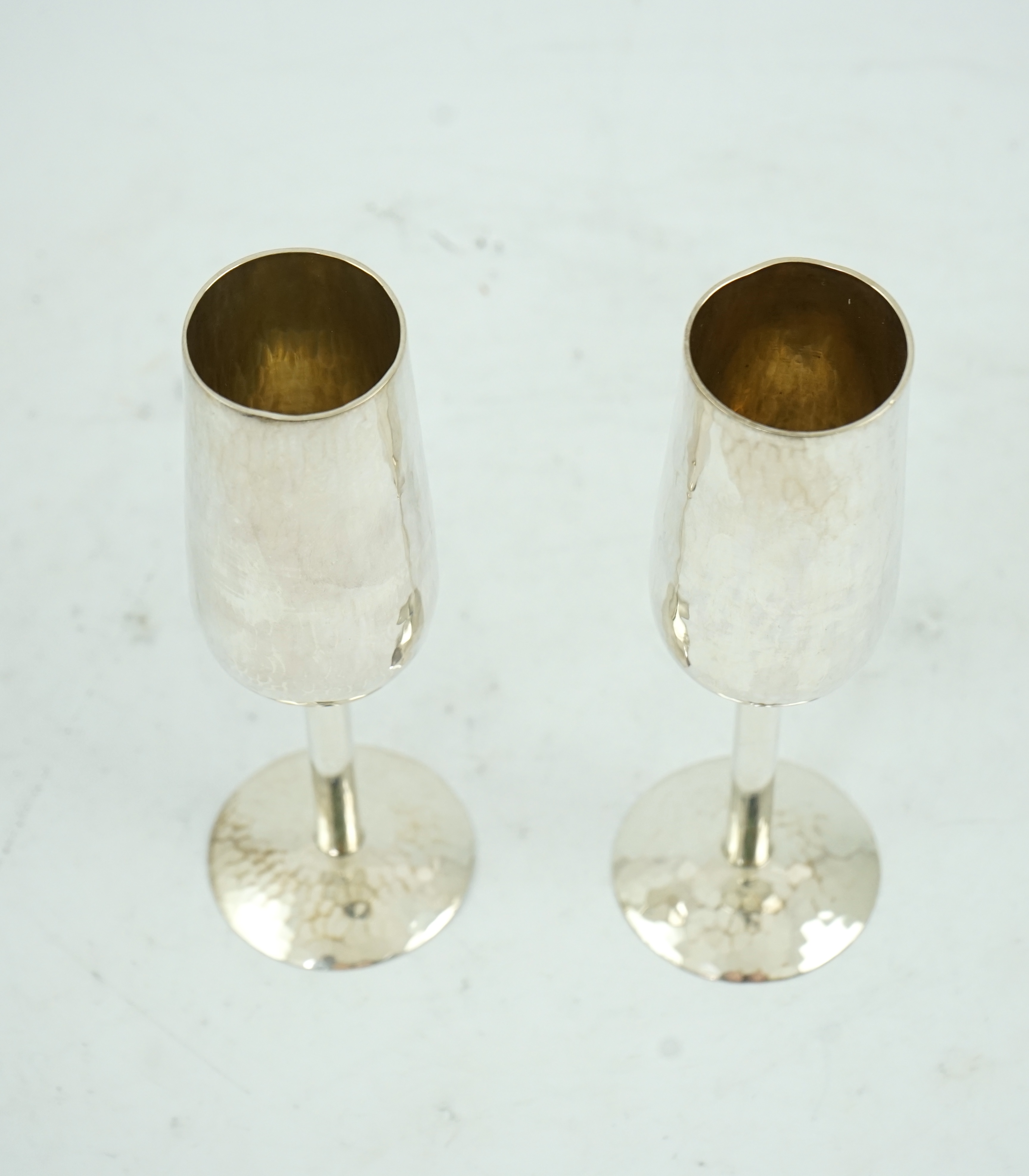 A pair of Elizabeth II planished silver champagne flutes, by Pruden & Smith